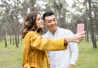 Man with beautiful woman taking selfie on smart phone at forest