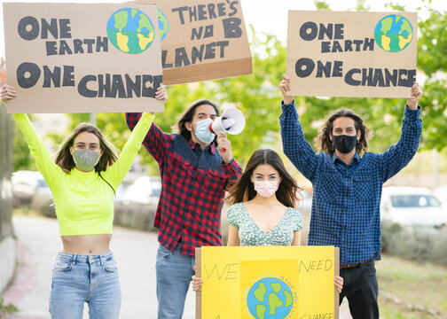 Men with women holding banner sign while protesting on climate change at footpath during pandemic