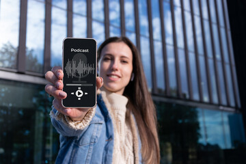 Podcast application. Audio podcast on mobile smartphone screen application in woman hand. Happy young sexy girl holding recording sound voice equipment background. Broadcast media music concept.