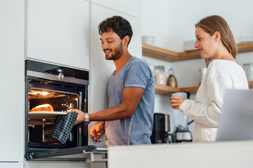 Man with girlfriend preparing croissant in kitchen at home