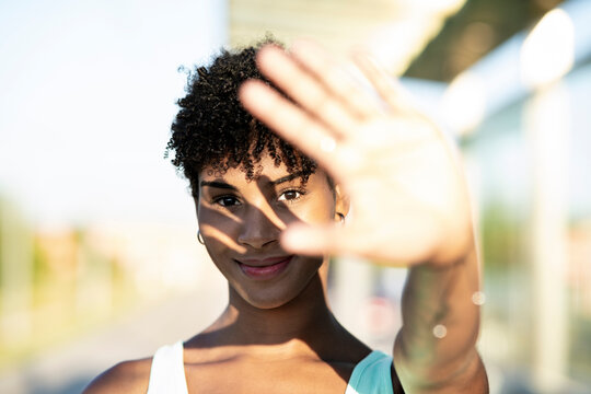 Young woman shielding eyes from sunlight outdoors