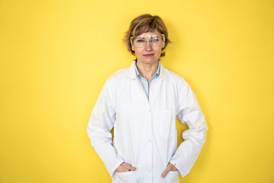 Mature female professional with hands in pockets leaning on wall