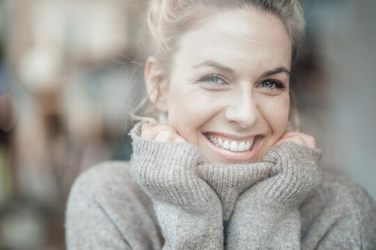Mid adult woman wearing sweater smiling with hand on chin