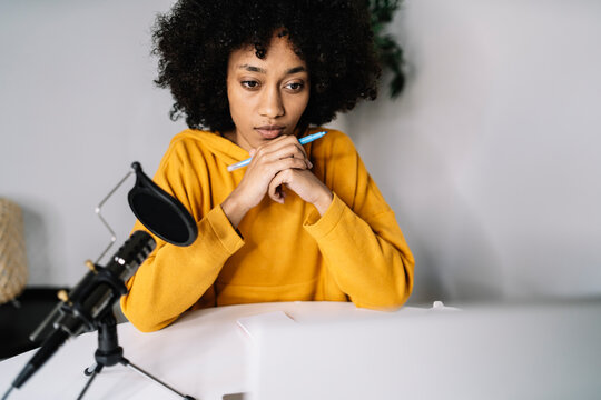 Concentrated woman with felt tip pen podcasting at home