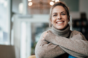 Mid adult woman wearing sweater smiling at cafe