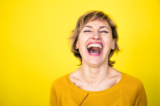 Woman laughing in front of yellow background