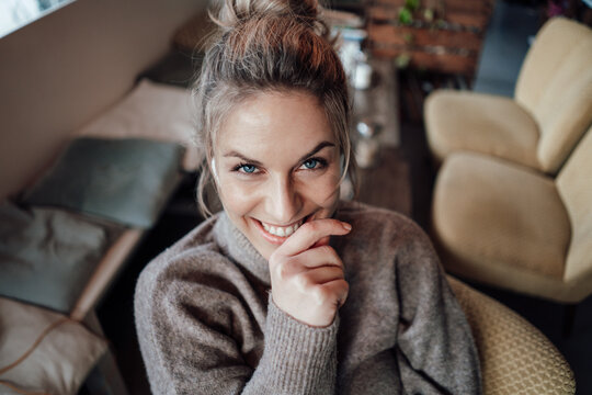Smiling beautiful woman with hand on chin at cafe