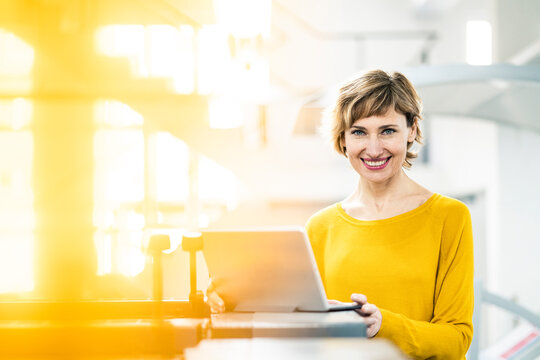 Smiling businesswoman with laptop in printing workshop