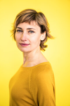 Beautiful woman with highlights - hair staring by yellow background