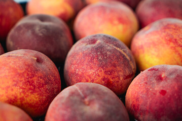 Peaches in a black box. Many peaches on the market. Box full of fresh picked peaches. Close-up of colorful fruit. Organic food for health. Vitamins. Depth of field