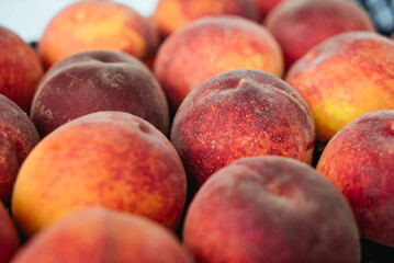Peaches in a black box. Many peaches on the market. Box full of fresh picked peaches. Close-up of colorful fruit. Organic food for health. Vitamins. Depth of field