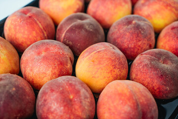 Peaches in a black box. Many peaches on the market. Box full of fresh picked peaches. Close-up of colorful fruit. Organic food for health. Vitamins. Depth of field
