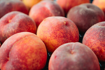 Peaches in a black box. Many peaches on the market. Box full of fresh picked peaches. Close-up of colorful fruit. Organic food for health. Vitamins. Depth of field