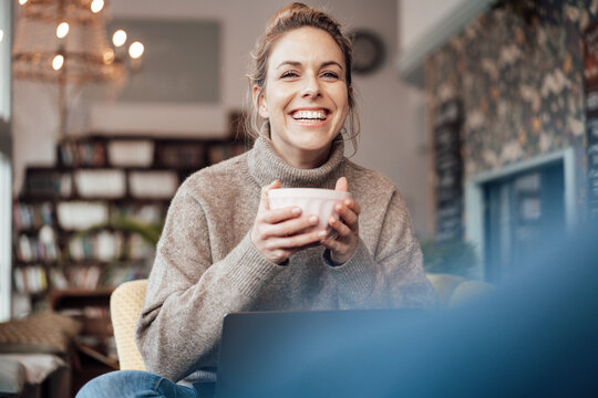 Smiling female customer with coffee sitting at cafe