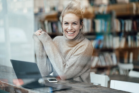Cheerful businesswoman with laptop at cafe