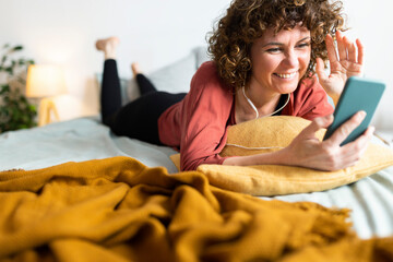 Smiling woman doing video call through smart phone in bedroom