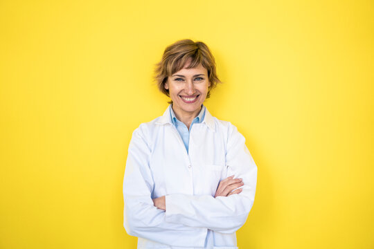 Smiling Female Scientist Standing With Arms Crossed In Front Of Wall