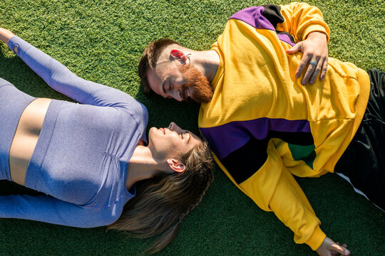 Smiling man lying by woman on grass during sunny day