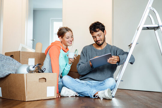 Young couple discussing over digital tablet at new home
