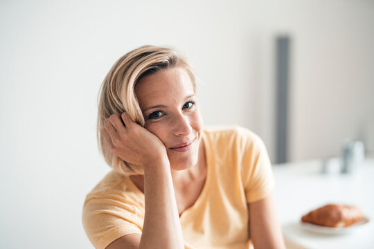 Blond hair woman with head in hand at home