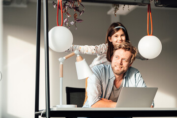 Smiling daughter piggybacking on father day dreaming at home