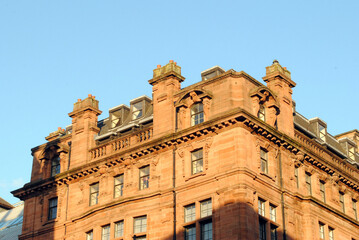 Fototapeta na wymiar Roofline of Victorian Stone Office Building seen in Warm Evening Light against Blue Sky 