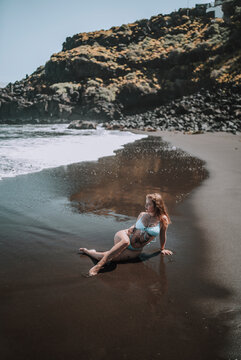 Chica veraniega surfera en playa cala de arena negra en las islas canarias paraiso