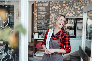 Cheerful businesswoman standing at cafe entrance