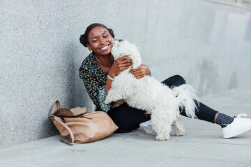 Smiling woman playing with dog while sitting on footpath