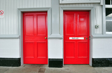 Fototapeta na wymiar Two red Painted Wooden Doors on Platform of Old Railway Station 