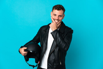 Naklejka premium Caucasian man with a motorcycle helmet isolated on blue background happy and smiling