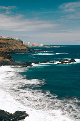 Acantilado de playa de arena negra en el norte de la isla canaria de tenerife con hoteles de fondo en verano