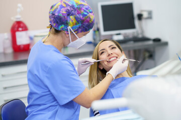 Female dentist examining patient's teeth at clinic during pandemic