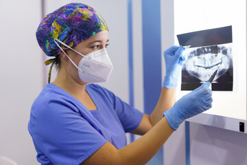 Female dentist examining medical x-ray at clinic during pandemic