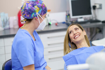 Smiling female patient talking with dentist at clinic