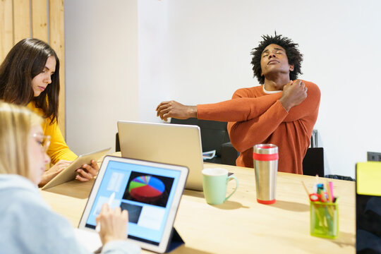 Creative businessman stretching at table in office