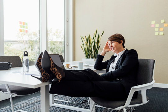 Female professional with head in hands looking away while sitting at desk in office
