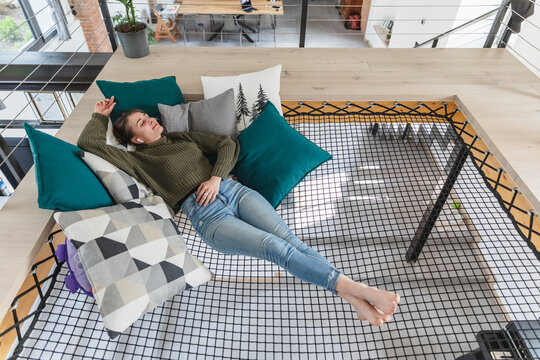 Relaxed young woman lying on hammock in modern home