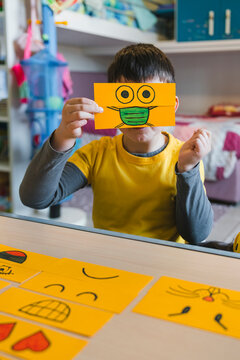 Boy playing with COVID-19 emoticon in playroom at home