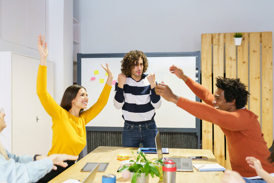 Happy business professionals cheering in board room at office