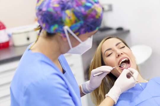 Female dentist wearing surgical gloves examining patient's teeth at medical clinic