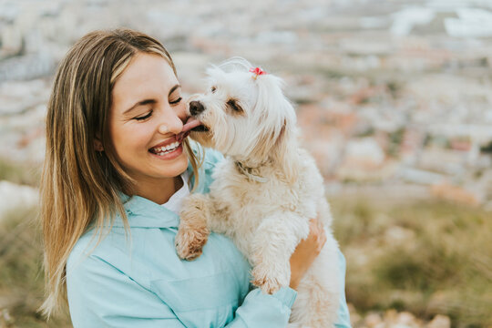Cheerful woman smiling while holding maltese dog