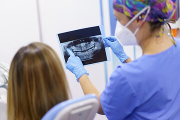 Female dentist explaining medical x-ray to patient at clinic