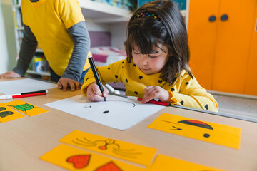 Girl drawing smiley face on paper while playing at home