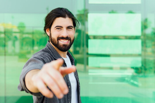 Smiling young man gesturing while standing in front of glass wall