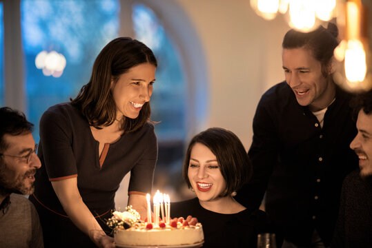 Happy male and female friends cheering during birthday celebration at home
