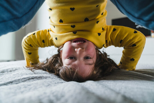Playful girl doing headstand at home