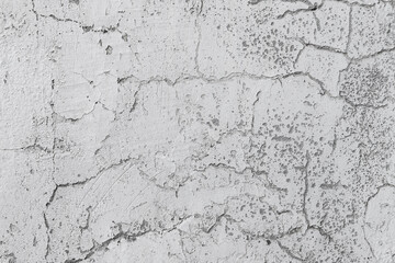 Grungy white concrete wall with cracks in plastering