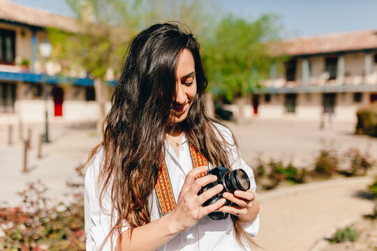 Smiling female tourist holding camera on sunny day