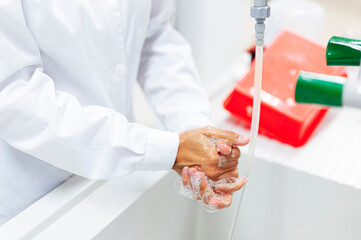 Mature medical expert washing hands in lab